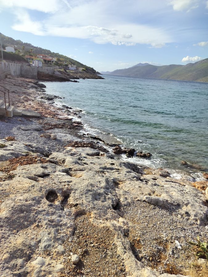 Rocky coastal path near Porto Germeno with houses along the shore