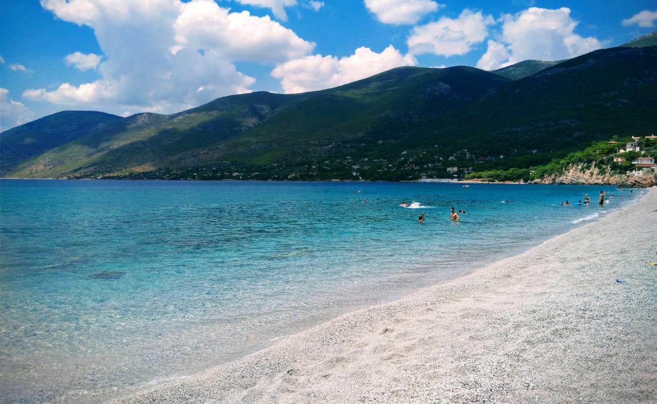 Turquoise water and pebble beach at Porto Germeno, backed by pine-covered mountains