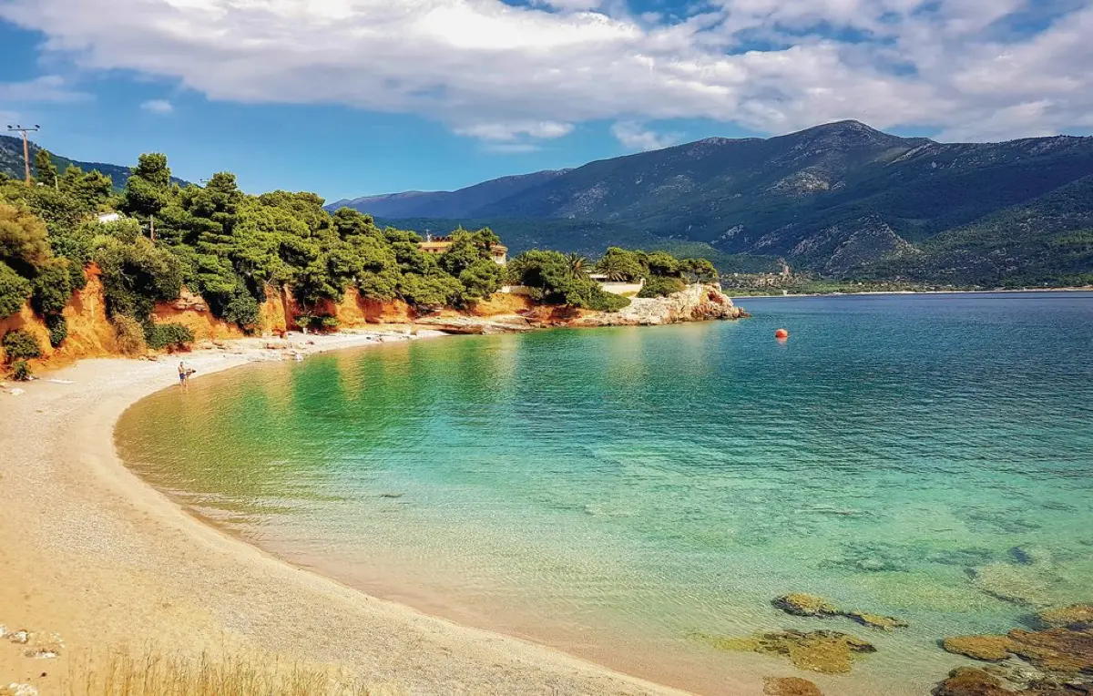 Small cove with red cliffs and clear green-blue water near Porto Germeno